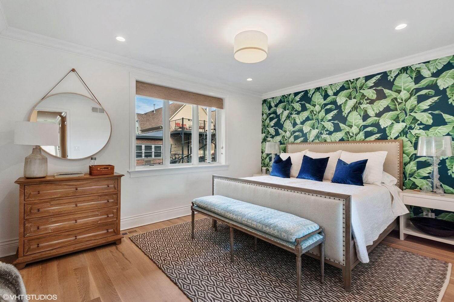Bright bedroom with tropical wallpaper and modern furnishings.