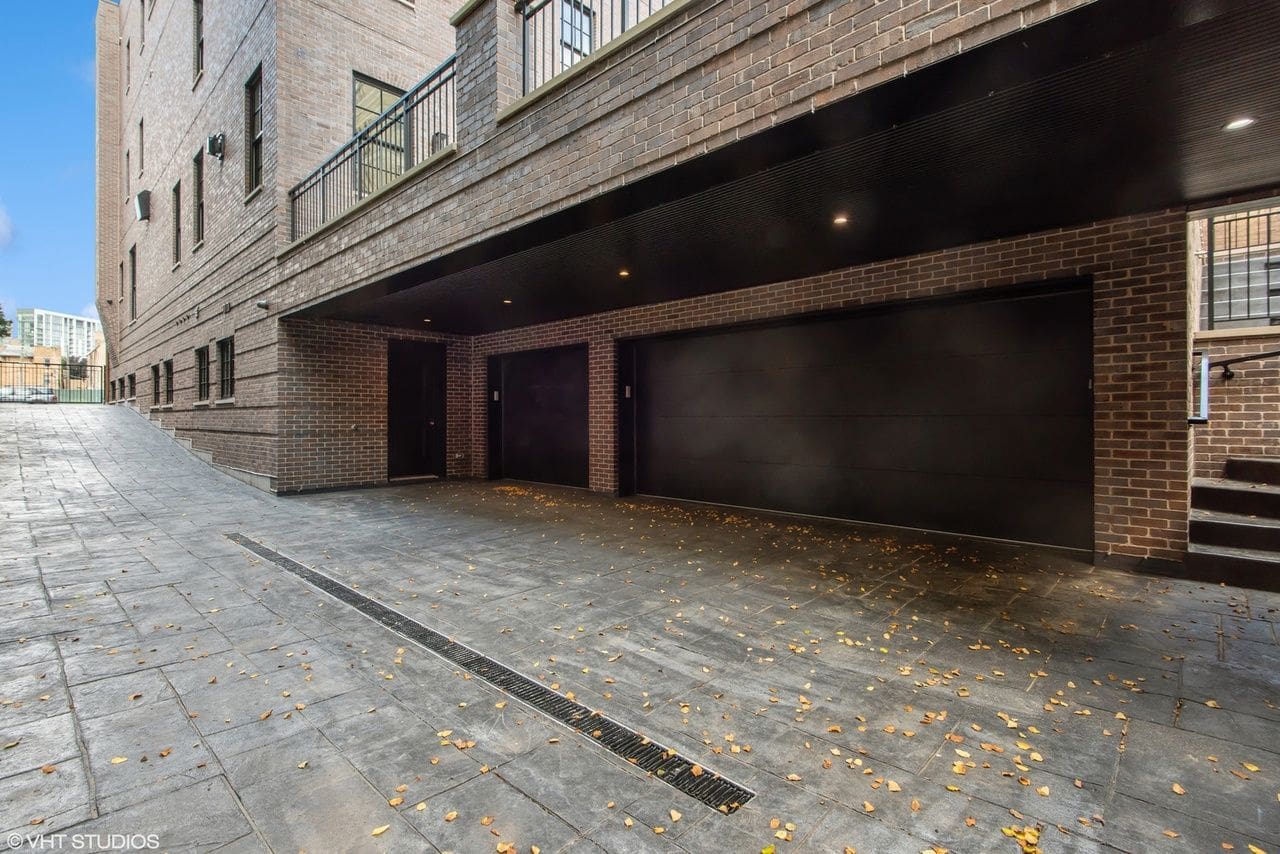 Empty building entrance with closed shutters and wet pavement.