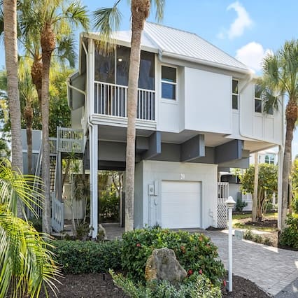 Elevated white house with palm trees.