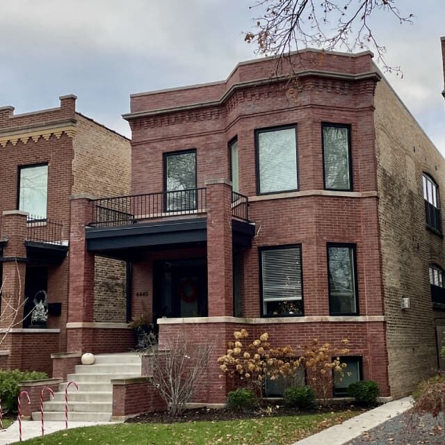 A brick townhouse with a bay window and small front porch.