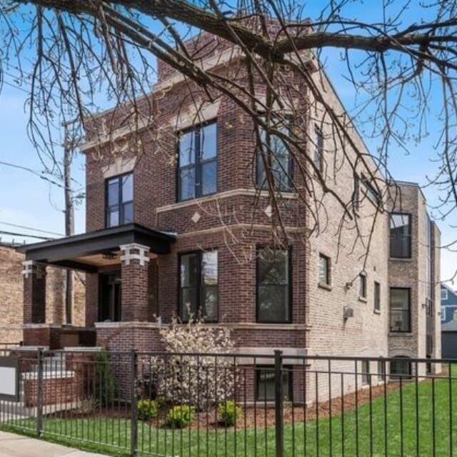 A two-story brick house with a porch and black fence.