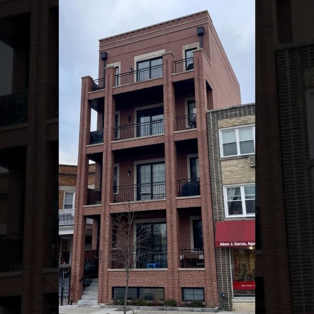A modern three-story brick building with large windows and balconies.